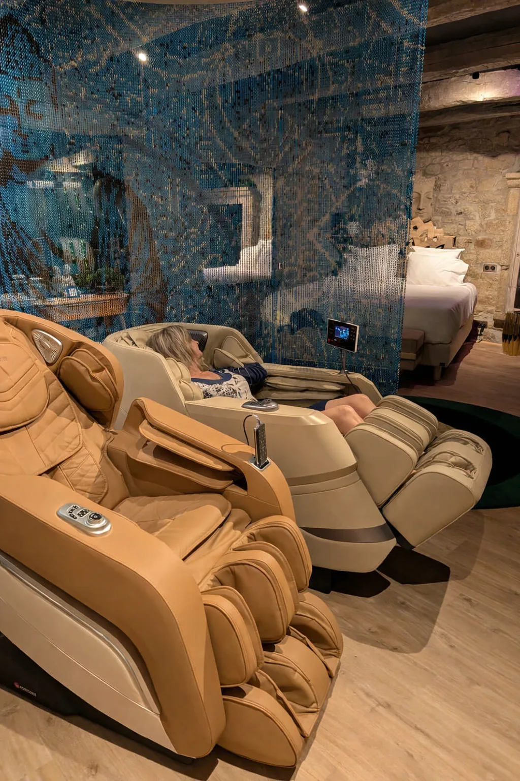 Espace bien‑être de la Suite Samadhi avec fauteuils massants haut de gamme, rideau Bouddha bleu et lumière douce pour détente totale.
