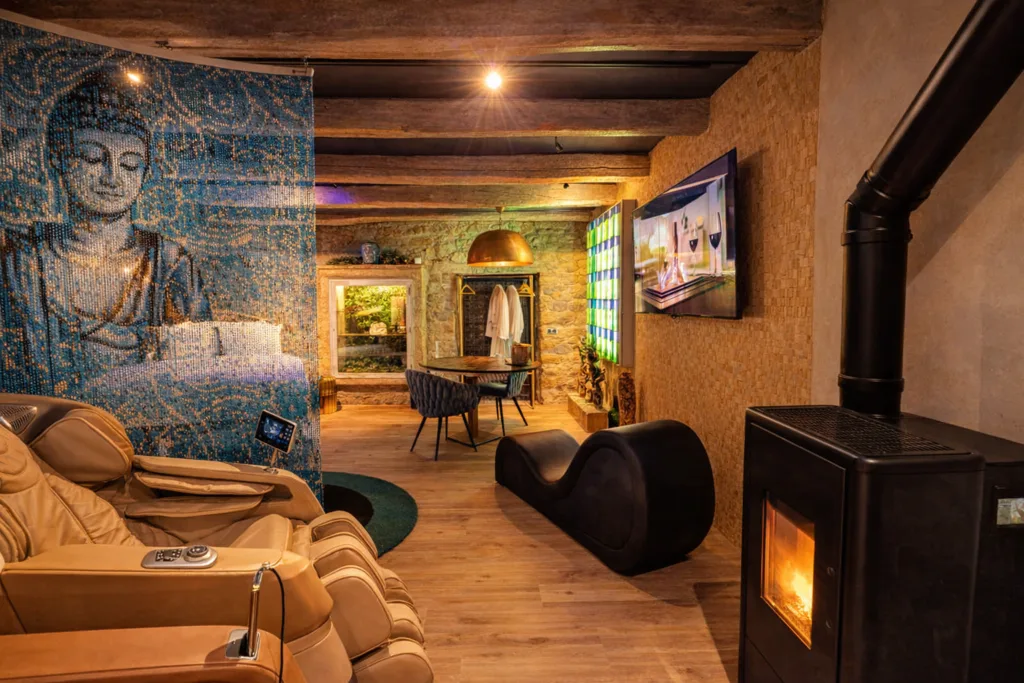 Intérieur de la Suite Samadhi à Carnac, poêle à bois, fauteuil design et ambiance chaleureuse entre pierre, bois et lumière dorée.
