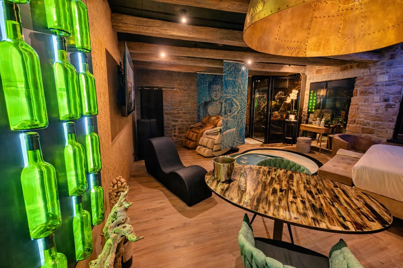 Espace détente de la Suite Samadhi avec mur de bouteilles vertes illuminées, mobilier design et atmosphère zen et contemporaine.
