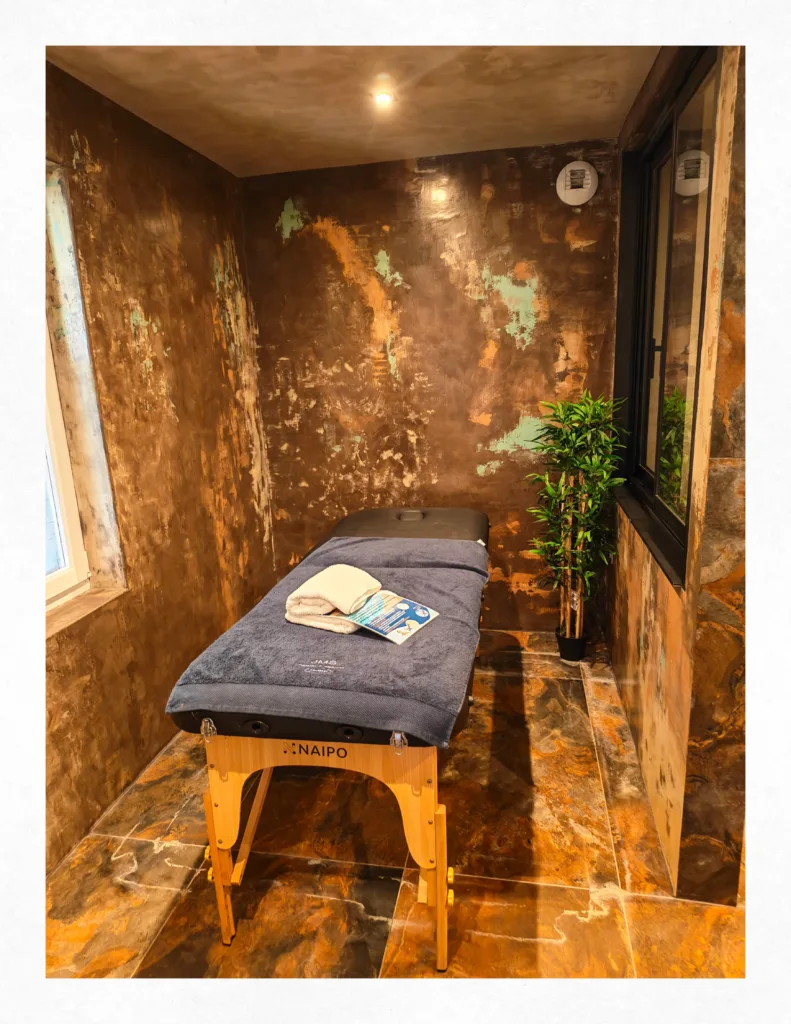 Table de massage Naipo avec serviettes dans une alcôve au design unique en béton ciré de la suite Ananda à Carnac.