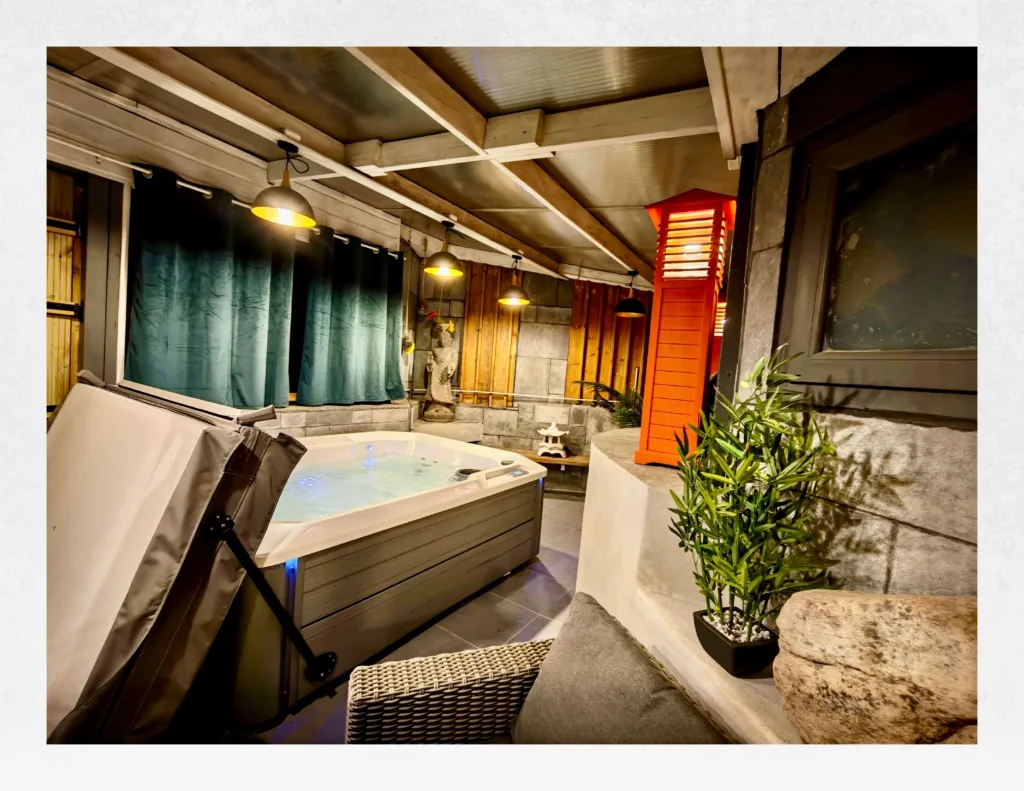 Ambiance nocturne lumineuse du grand spa privatif Hotspring sous le patio couvert de la suite Ananda à Carnac.