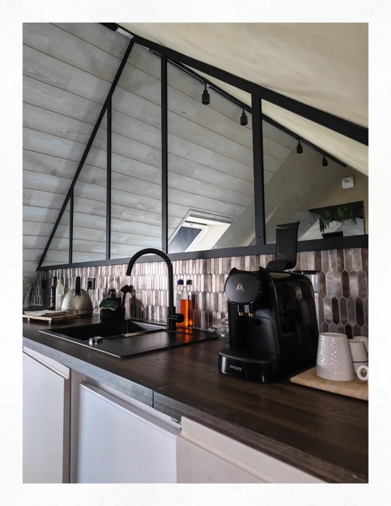 Espace cuisine équipée sous verrière de la suite Ananda avec machine à café Philips L'OR Barista et plan de travail en bois.